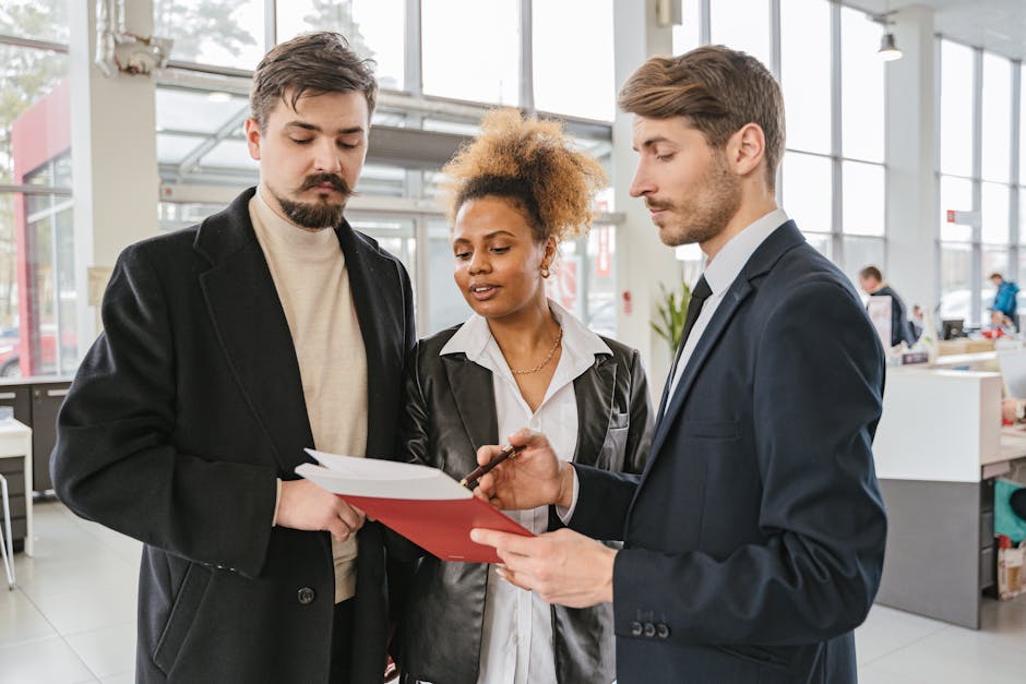 Three professionals discussing and reviewing documents in a modern office space.
