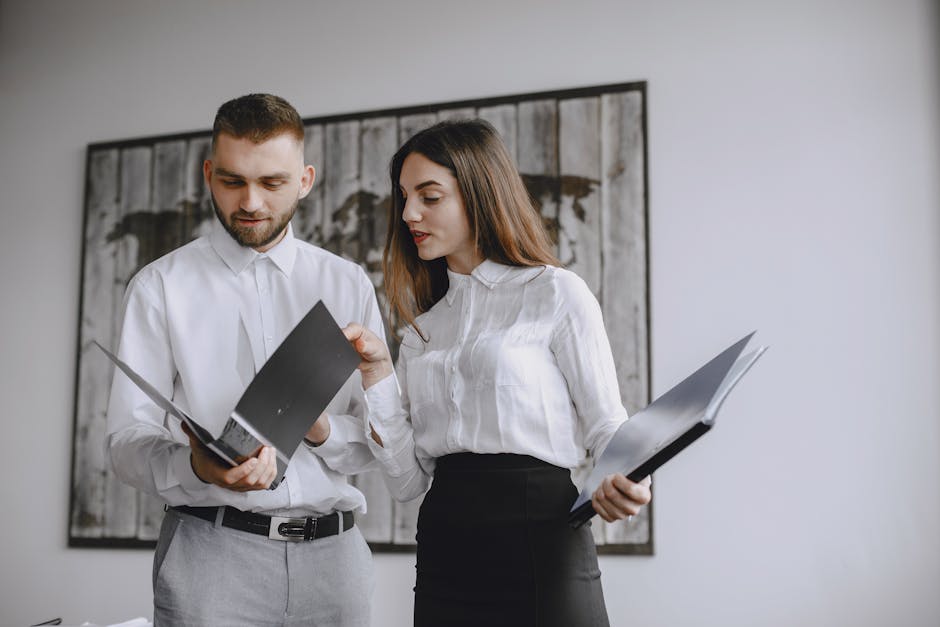Two colleagues in a modern office reviewing documents together.
